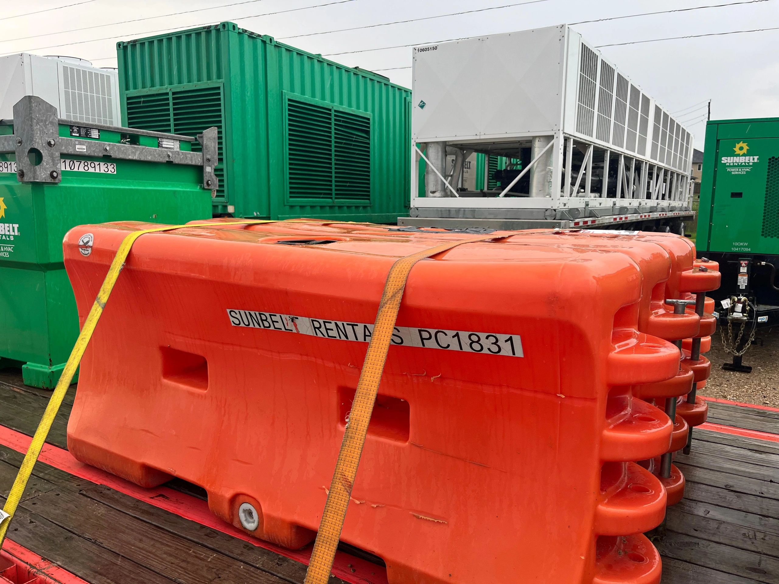 Yellow equipment tank on flatbed with pine trees