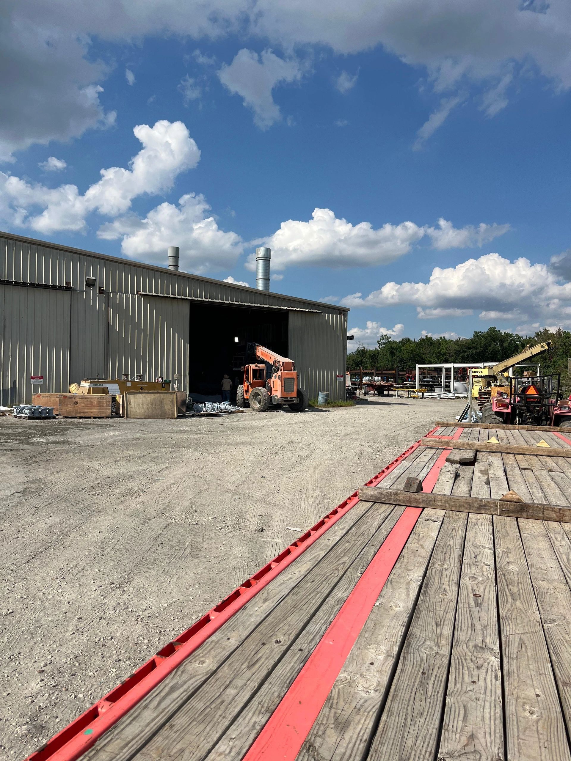 Industrial salvage yard with telehandler and warehouse