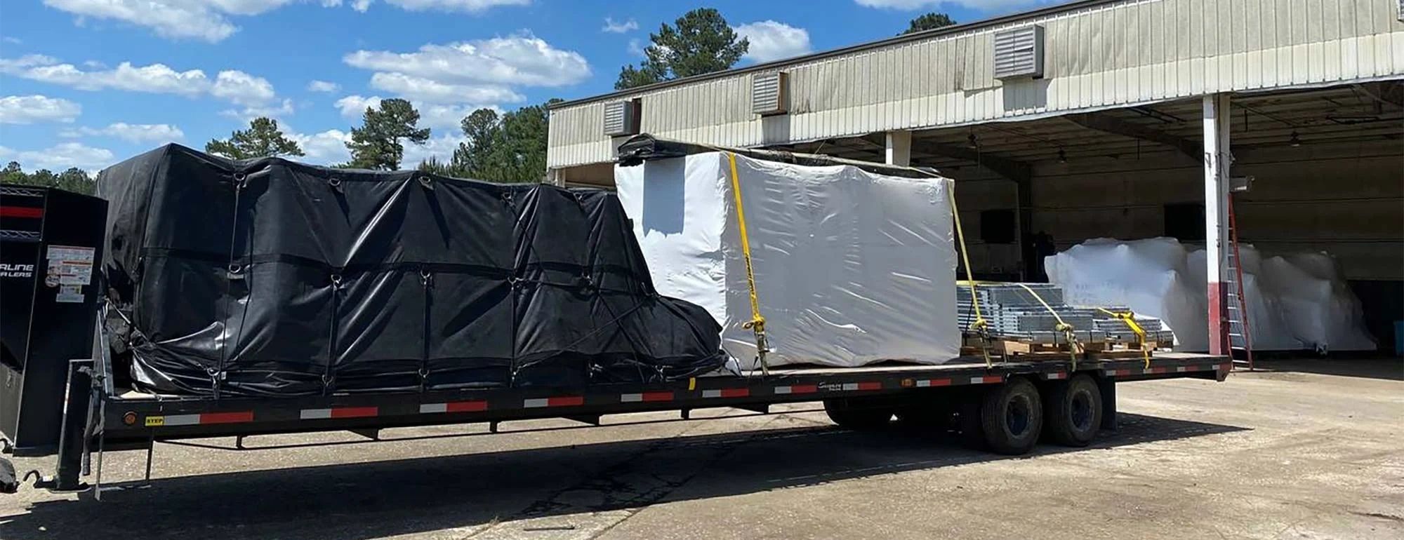 Flatbed semi-truck loaded industrial equipment warehouse